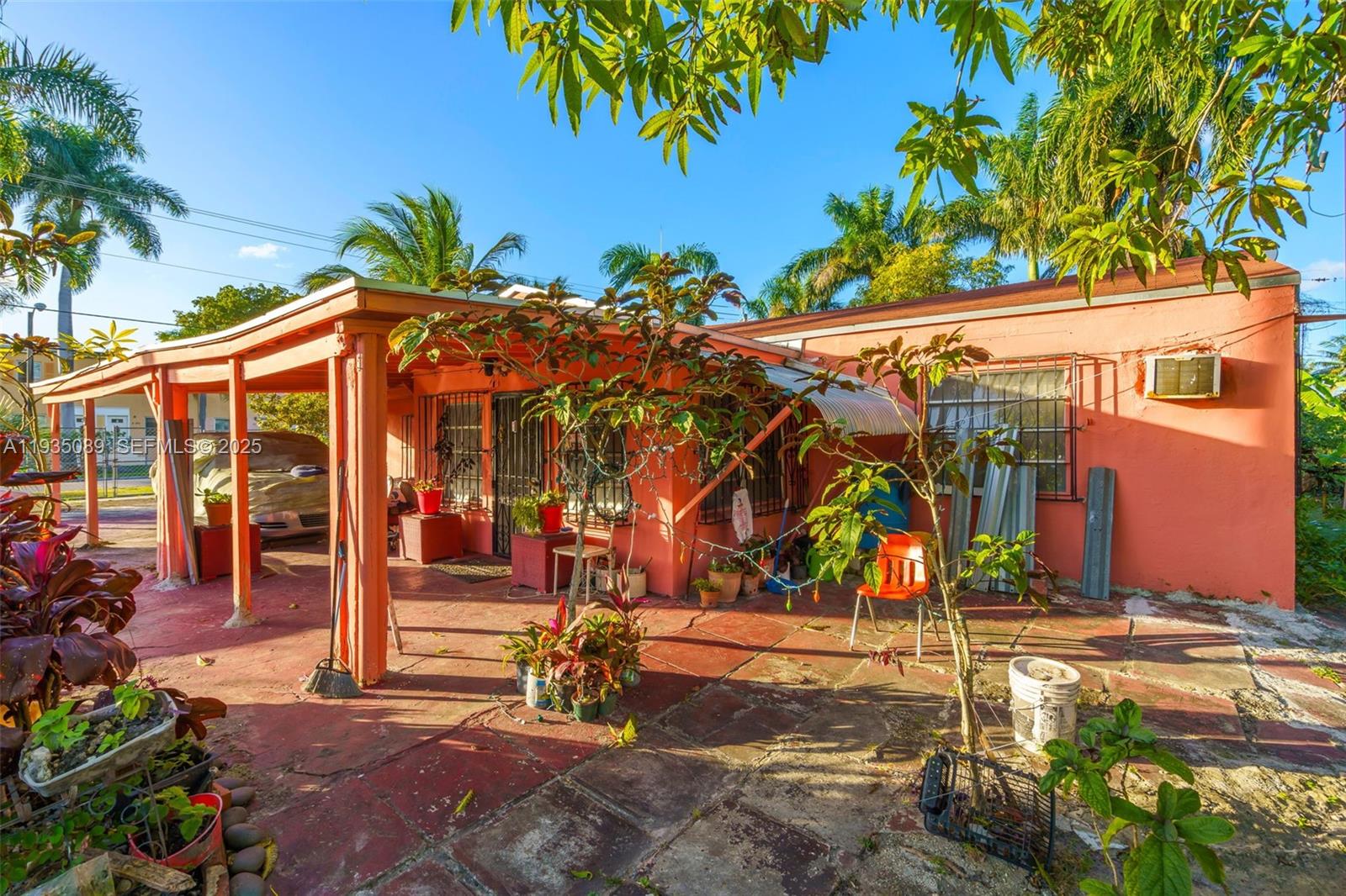 A peach-colored house features a covered patio with a tiled floor and potted plants — 191 NW 83rd St, Miami FL 33150, MIAMI, FL