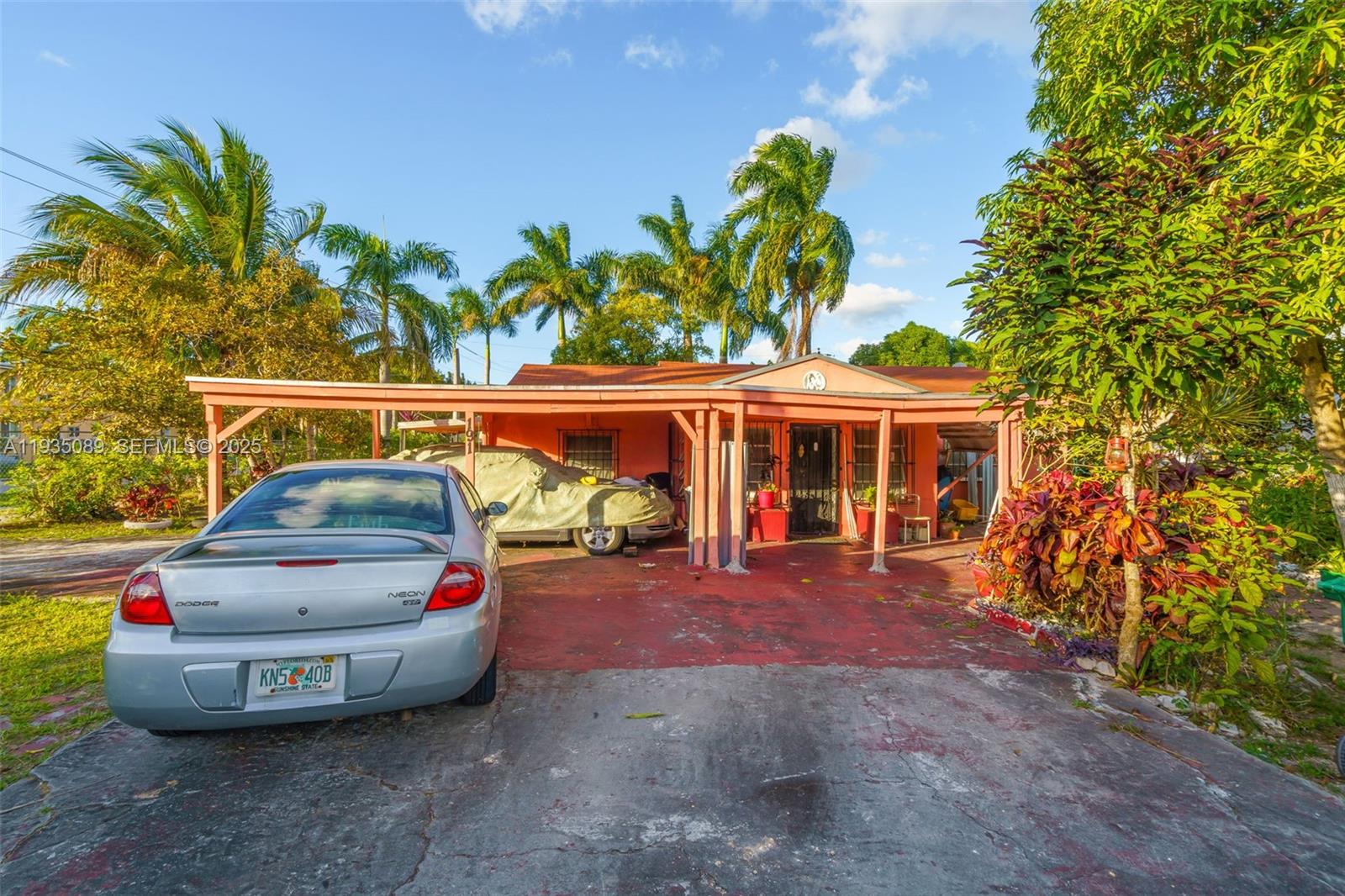A single-story peach-colored house features a covered carport and a concrete driveway with cars — 191 NW 83rd St, Miami FL 33150, MIAMI, FL