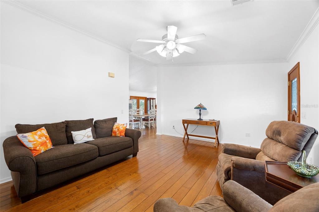 A living room features hardwood floors, a brown sofa, two armchairs, and a ceiling fan — 13015 ELM STREET, ODESSA, FL