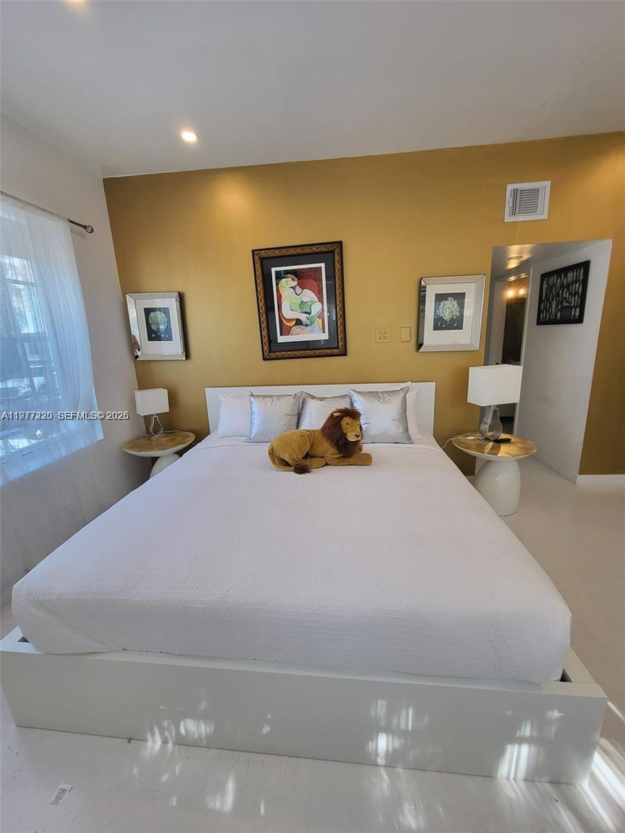 A bedroom features a white bed with a stuffed lion, gold wall, and framed art — 130 3rd St # 101, Miami Beach FL 33139, MIAMI BEACH, FL