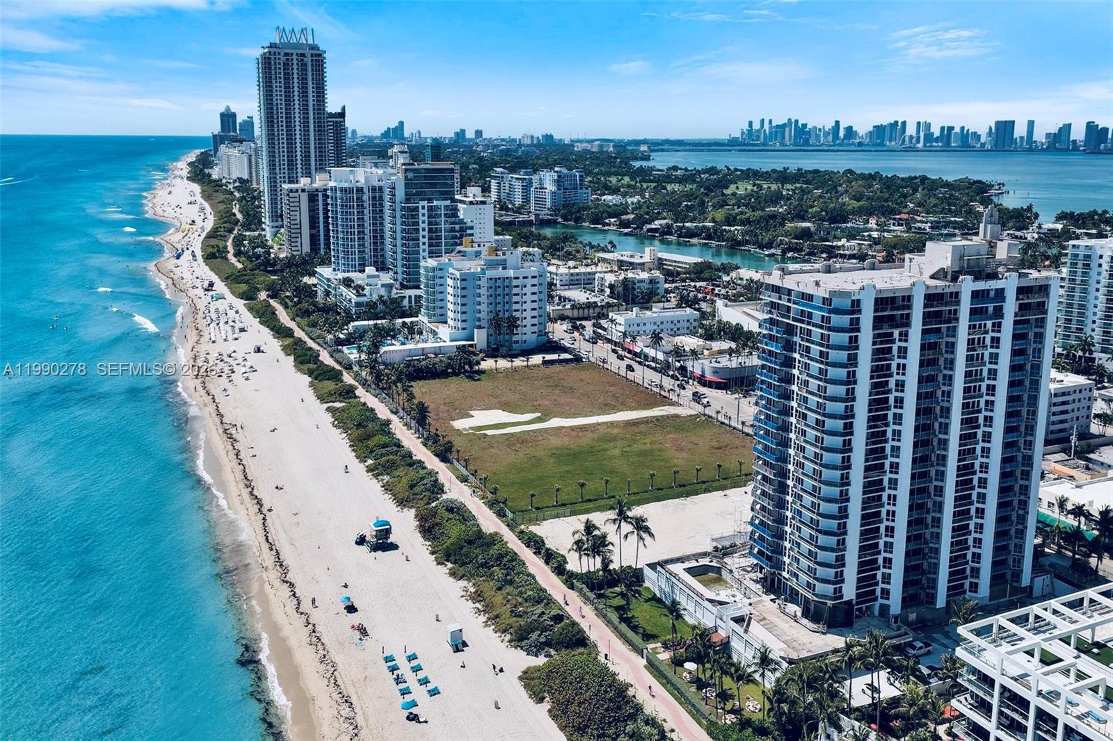 An aerial view shows a sandy beach, high-rise buildings, and a vacant lot in Florida — 6767 Collins Ave # 304, Miami Beach FL 33141, MIAMI BEACH, FL
