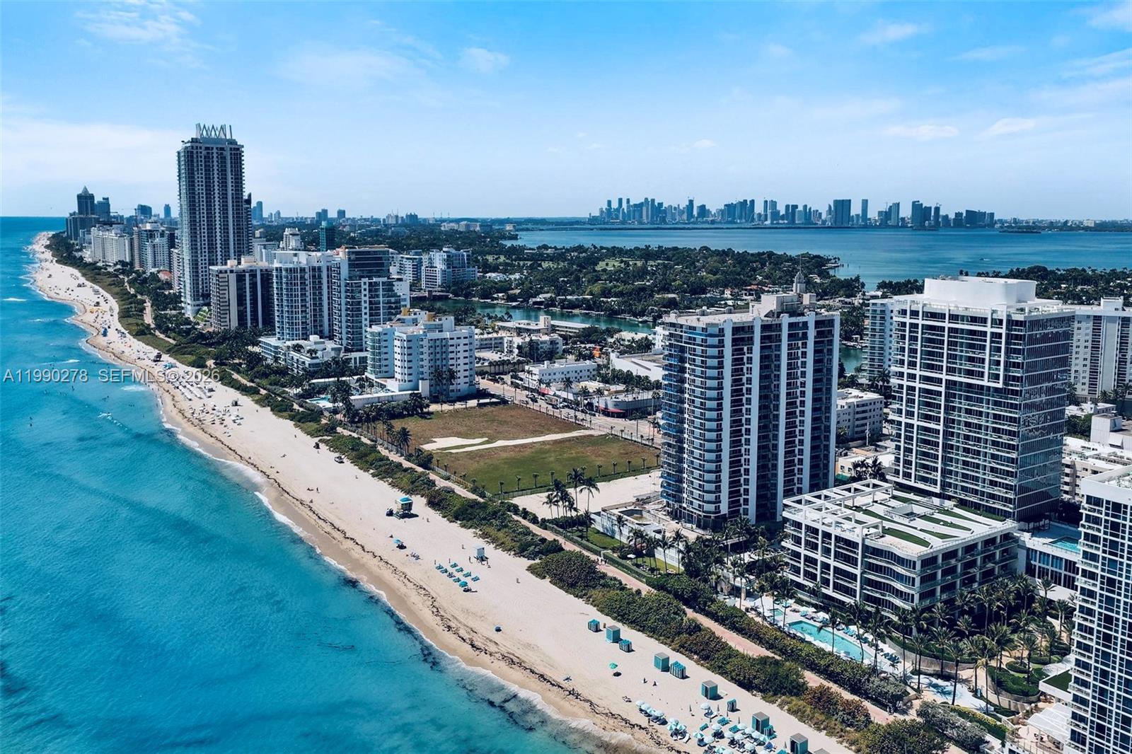 An aerial view of a coastal city featuring high-rise buildings along a sandy beach — 6767 Collins Ave # 304, Miami Beach FL 33141, MIAMI BEACH, FL