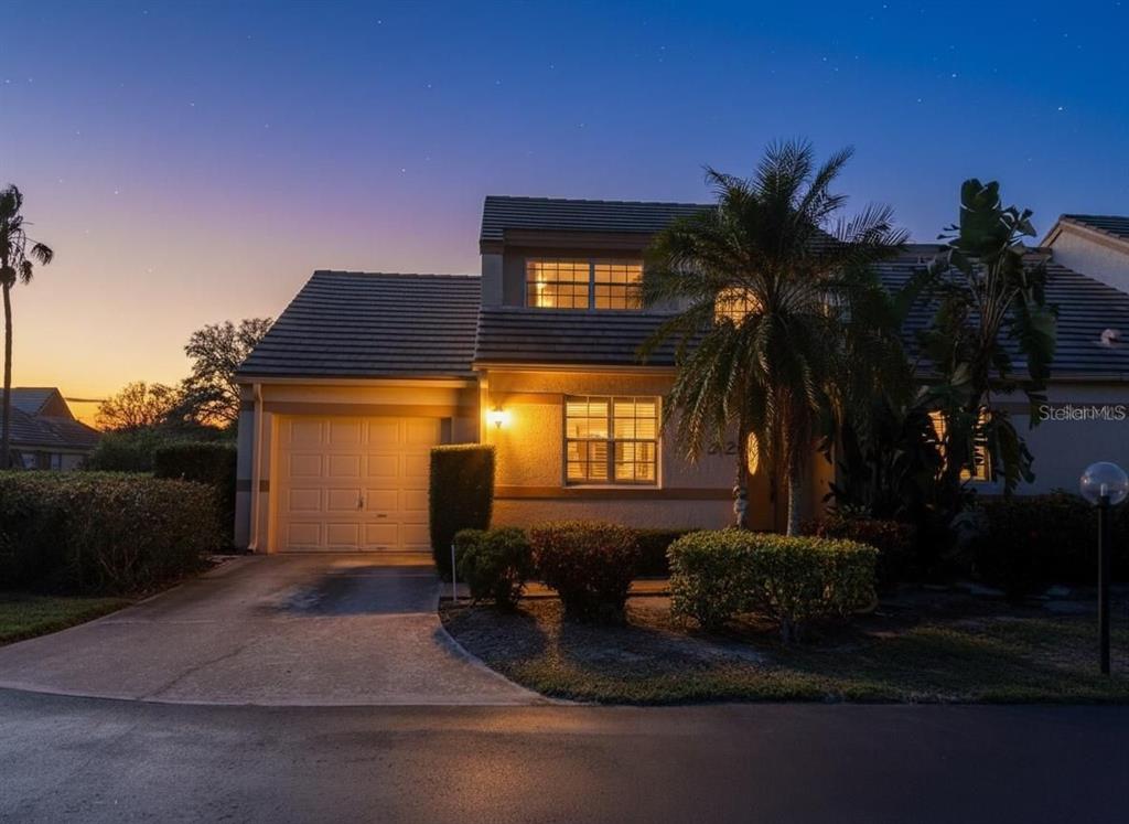 A two-story house with a garage, palm tree, and manicured landscaping at twilight — 3502 57TH AVE CIR W, BRADENTON, FL