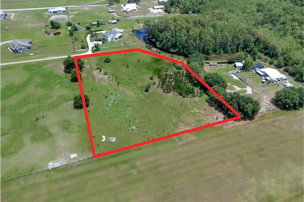 An aerial view shows a vacant, grassy rectangular lot outlined in red — ALBRITTON ROAD, ST CLOUD, FL