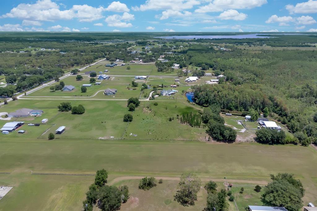 An aerial view shows a rural residential area with houses, pastures, and a grassy airstrip — ALBRITTON ROAD, ST CLOUD, FL