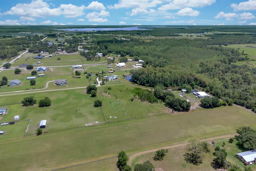 An aerial view shows a large grassy field, scattered houses, and dense trees under a sky — ALBRITTON ROAD, ST CLOUD, FL