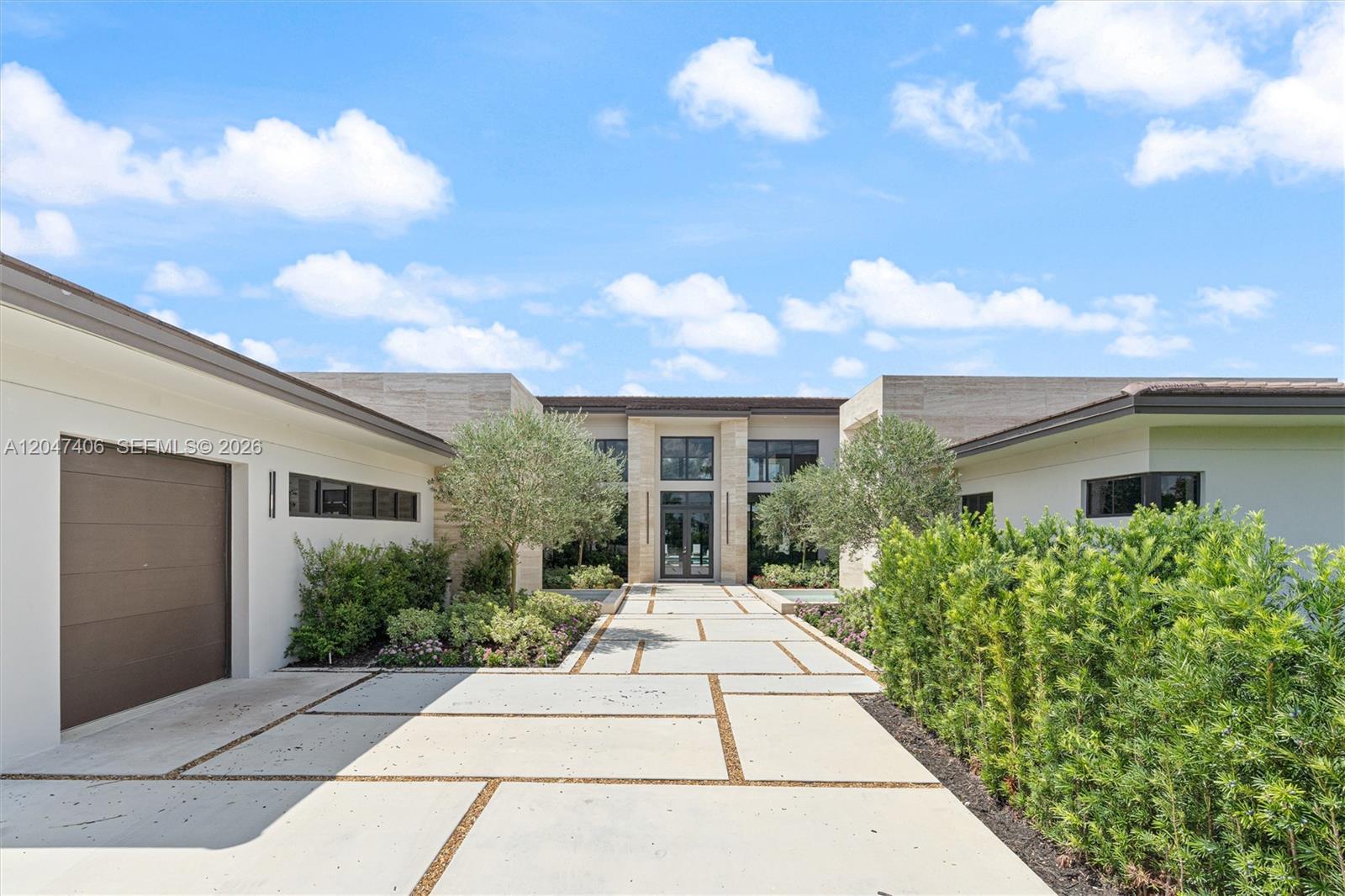 A modern house exterior features a concrete paver driveway, stone accents, and manicured landscaping — 14930 SW 16th Ct, Davie FL 33326, DAVIE, FL