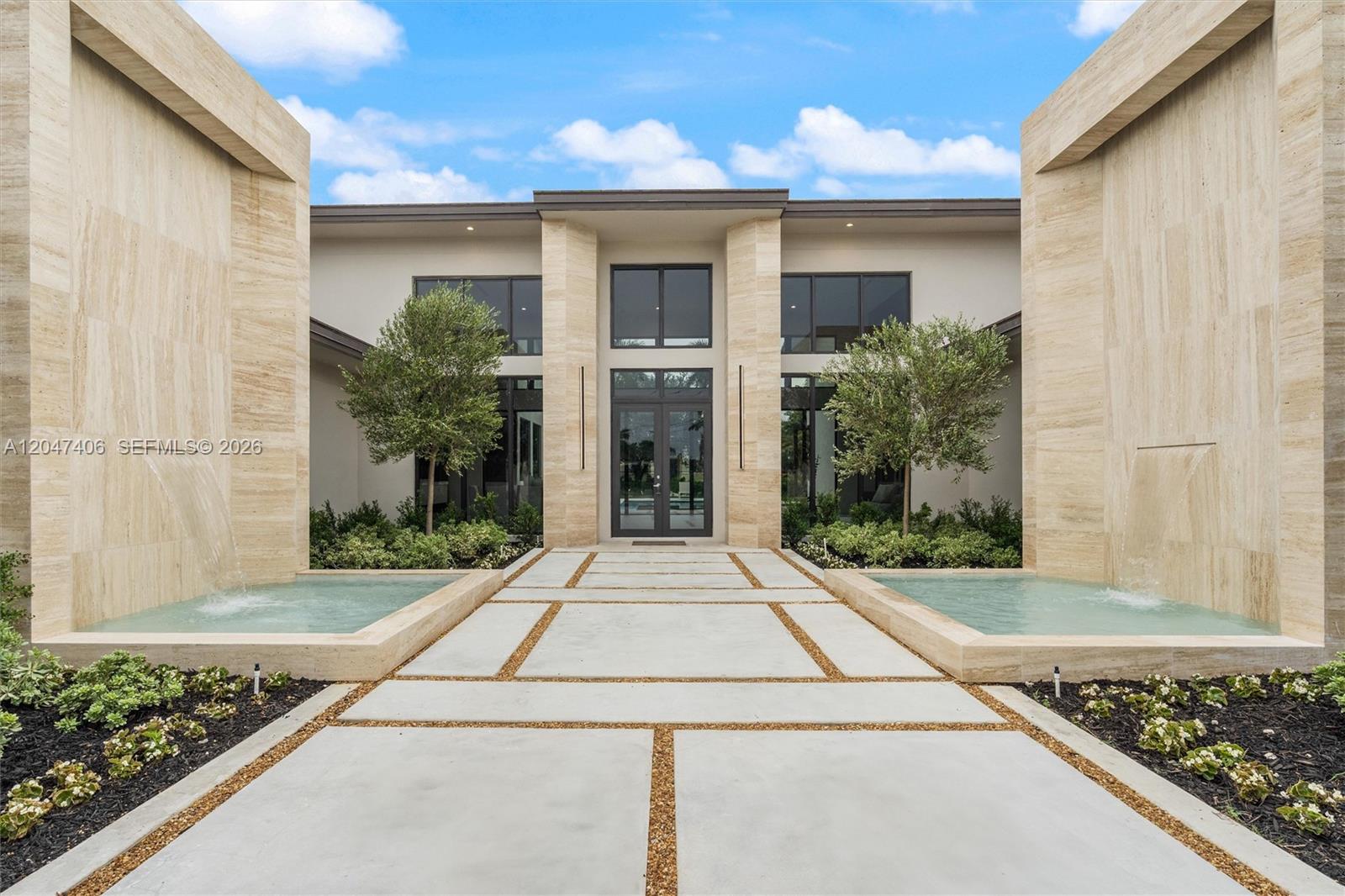 A modern home entrance features a concrete walkway flanked by two stone water features — 14930 SW 16th Ct, Davie FL 33326, DAVIE, FL