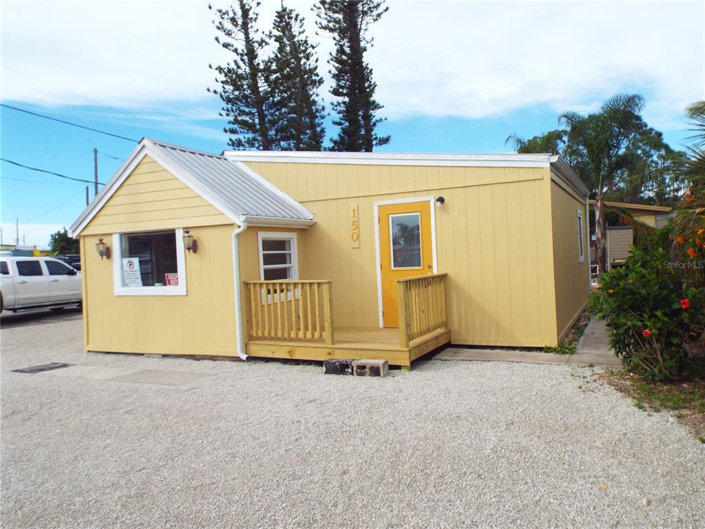 A yellow, single-story building with a metal roof and a small wooden front porch — 150 E BAY HEIGHTS ROAD, ENGLEWOOD, FL