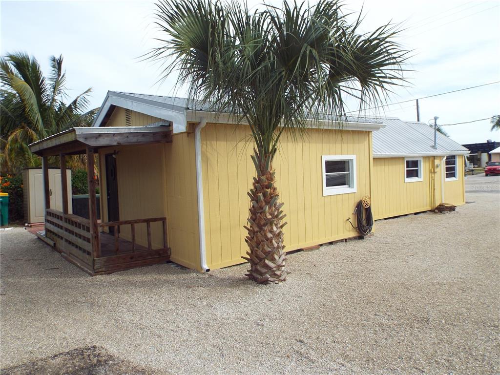 A yellow exterior building with a covered wooden porch and a palm tree in front — 150 E BAY HEIGHTS ROAD, ENGLEWOOD, FL