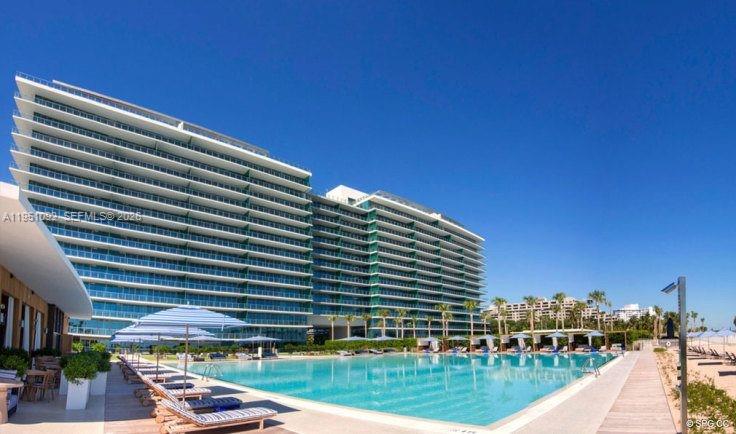 A large modern apartment building overlooks a swimming pool with lounge chairs and umbrellas — 350 Ocean Dr # 205N, Key Biscayne FL 33149, KEY BISCAYNE, FL