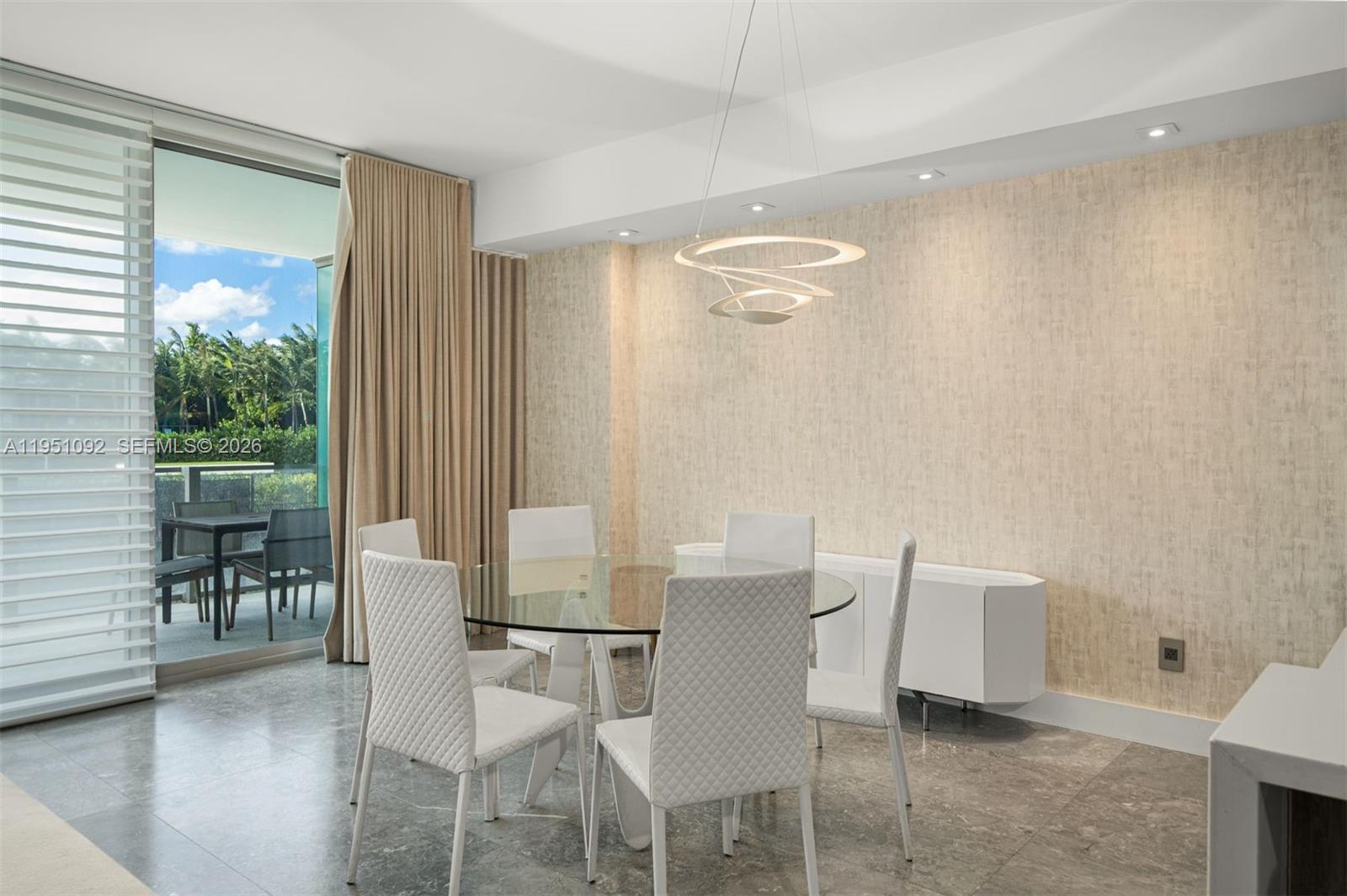 A dining room features a glass table, white chairs, a modern chandelier, and balcony access — 350 Ocean Dr # 205N, Key Biscayne FL 33149, KEY BISCAYNE, FL