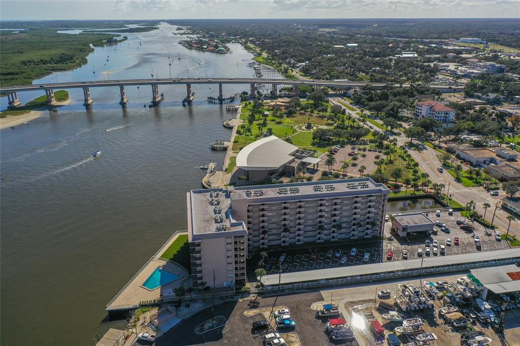An aerial view shows a waterfront high-rise apartment building next to a bridge and park — 101 N RIVERSIDE DRIVE UNIT 4120, NEW SMYRNA BEACH, FL