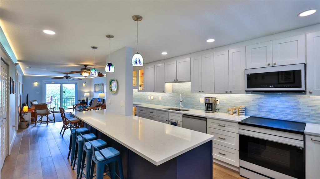A kitchen with white cabinets, a blue island, and a breakfast bar overlooks a living area — 101 N RIVERSIDE DRIVE UNIT 4120, NEW SMYRNA BEACH, FL