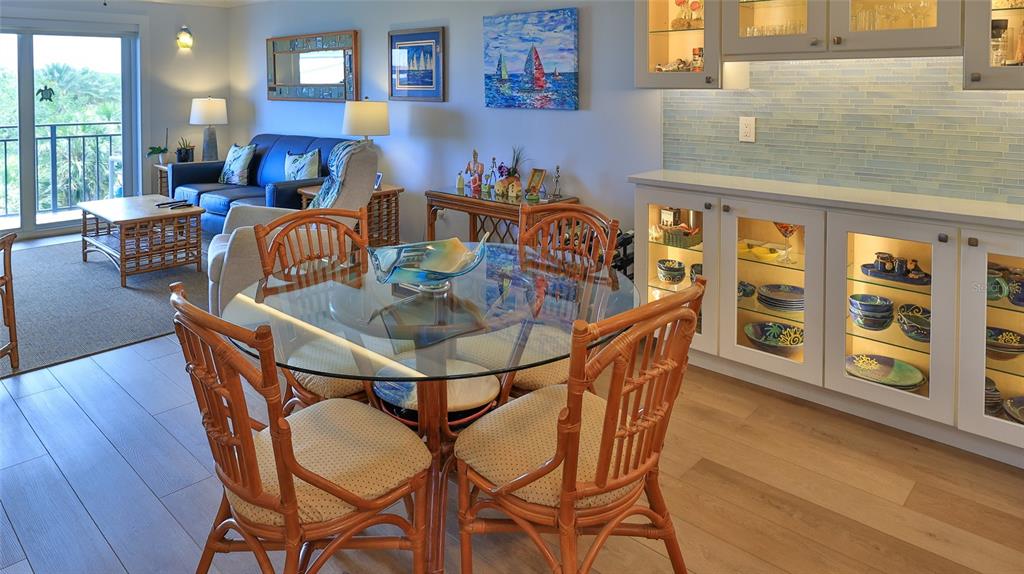 A dining area with a glass table and rattan chairs sits beside a built-in bar — 101 N RIVERSIDE DRIVE UNIT 4120, NEW SMYRNA BEACH, FL