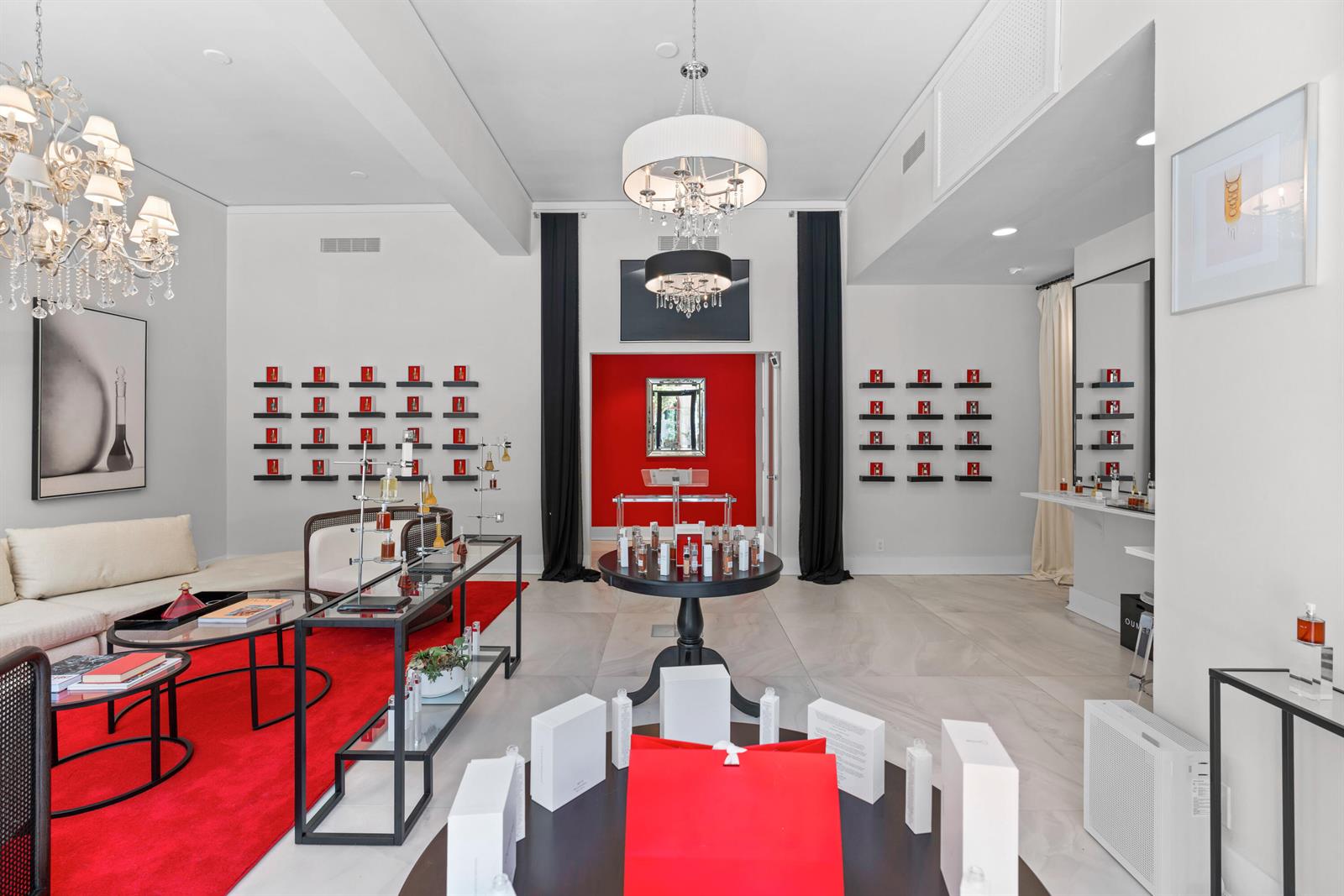A retail boutique features a red rug, display tables, wall-mounted shelves, and two crystal chandeliers — 256 Worth Avenue, Palm Beach FL 33480, PALM BEACH, FL