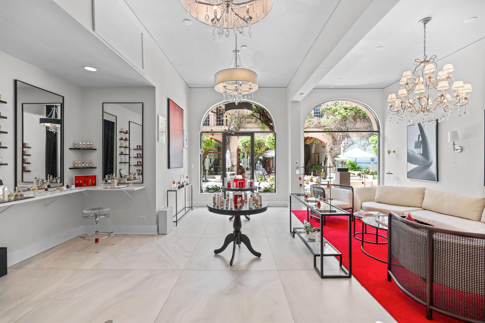 A bright retail boutique features chandeliers, a red rug, seating, and views of a courtyard — 256 Worth Avenue, Palm Beach FL 33480, PALM BEACH, FL