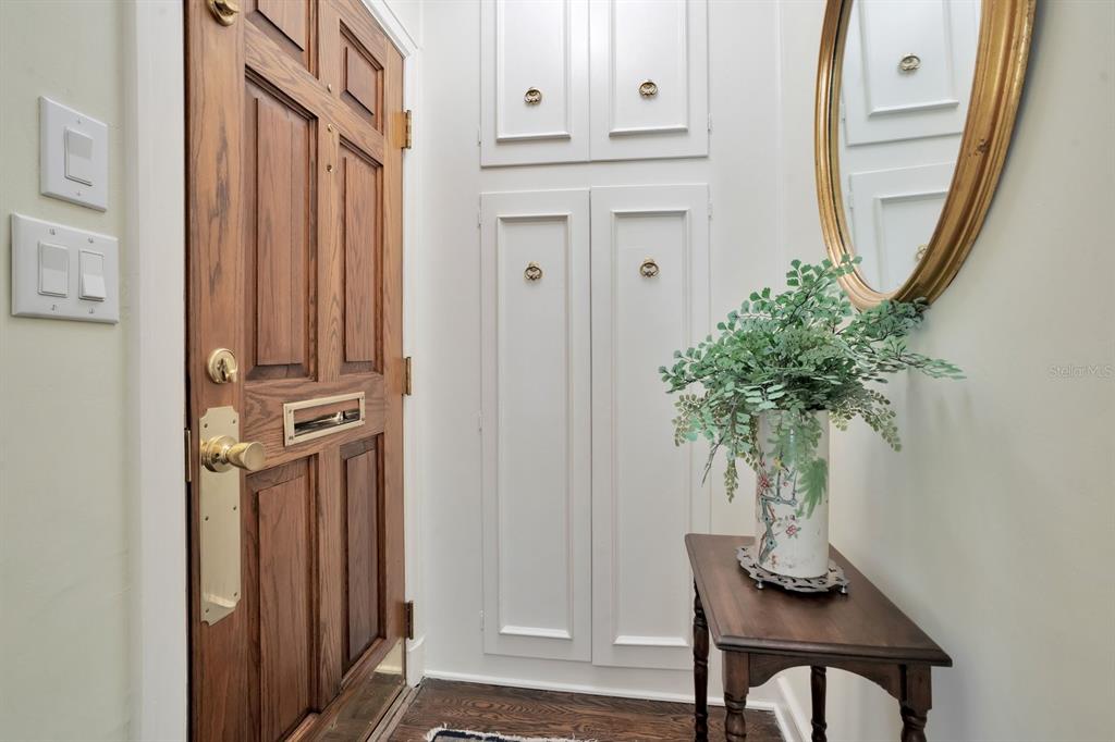 An entryway features a wood door, white built-in cabinets, a small wooden table, and mirror — 2109 CAMBRIDGE AVENUE, LAKELAND, FL