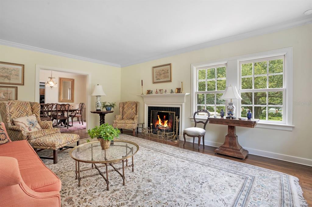 A living room with a fireplace, hardwood floors, a patterned rug, and a dining area beyond — 2109 CAMBRIDGE AVENUE, LAKELAND, FL