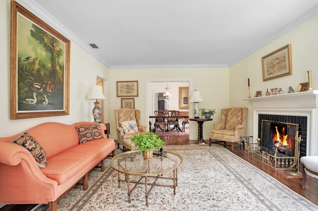 A living room with a coral sofa, fireplace, patterned rug, and a view into the dining room — 2109 CAMBRIDGE AVENUE, LAKELAND, FL