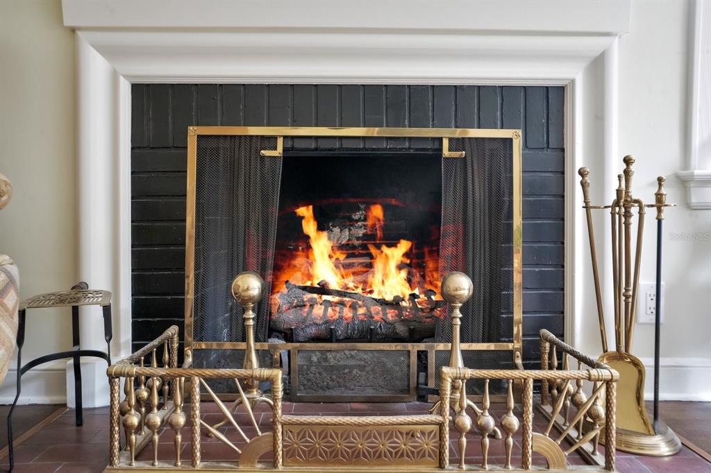 A fireplace with a black brick surround, brass screen, and brass fireplace tools on a hearth — 2109 CAMBRIDGE AVENUE, LAKELAND, FL