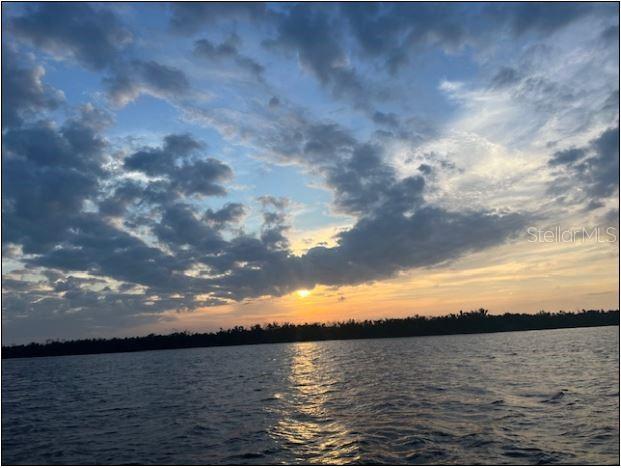 A sunset view over a body of water with a treeline in the distance — 18270 KERRVILLE CIRCLE, PORT CHARLOTTE, FL