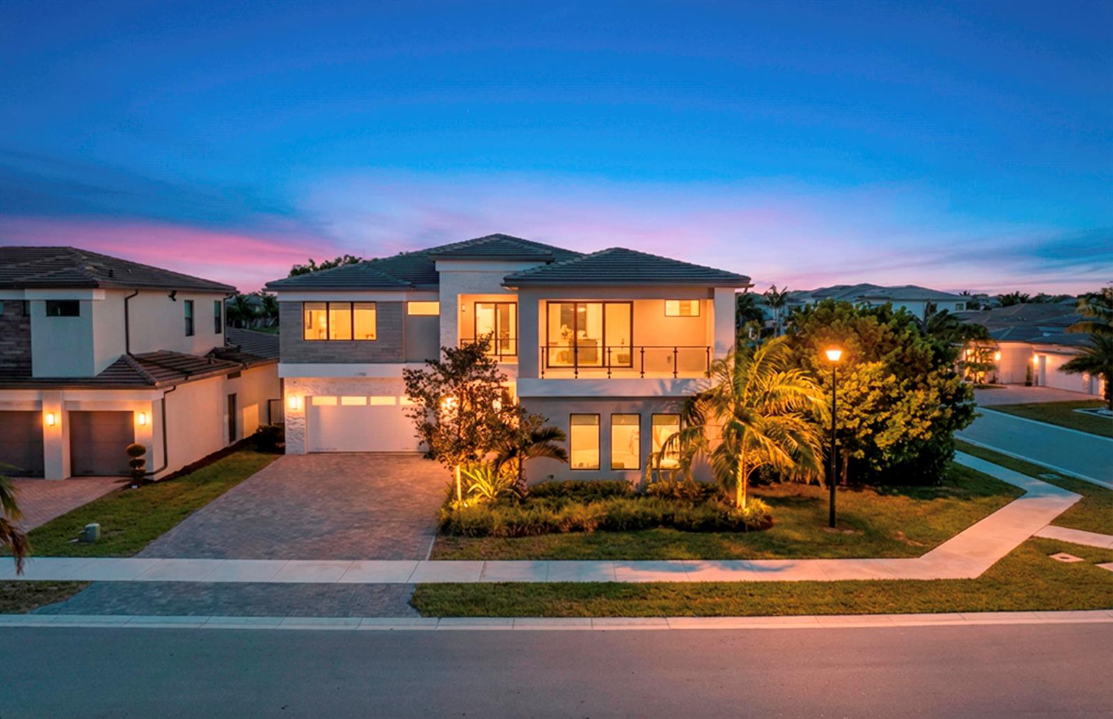 A two-story house with a paved driveway, balcony, and landscaping at dusk — 17081 Five Waters Avenue, Boca Raton FL 33496, BOCA RATON, FL
