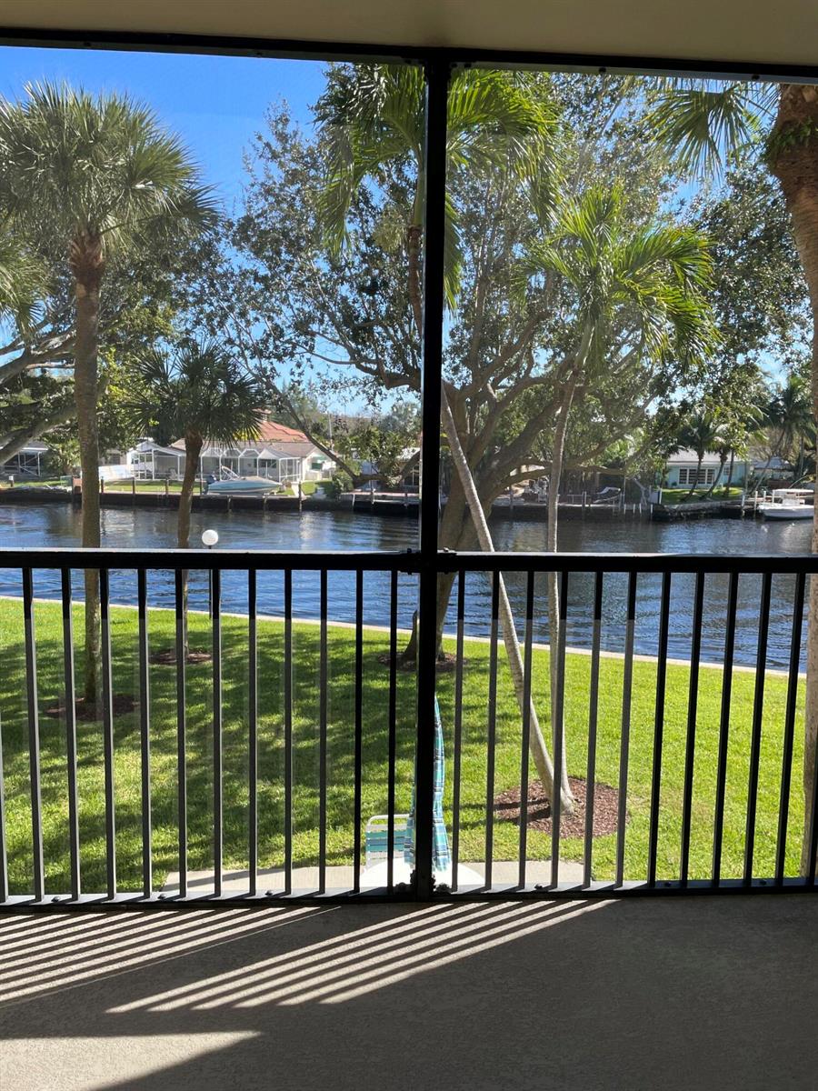 A view of a canal and palm trees from a screened-in balcony with metal railings — 14 Royal Palm Way # 204, Boca Raton FL 33432, BOCA RATON, FL