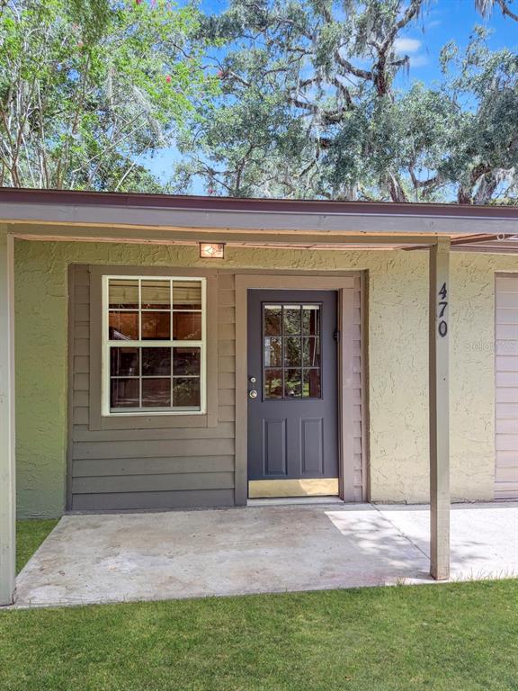 A dark gray front door and a window are set into a light green exterior wall — 470 FOREST AVENUE, BROOKSVILLE, FL