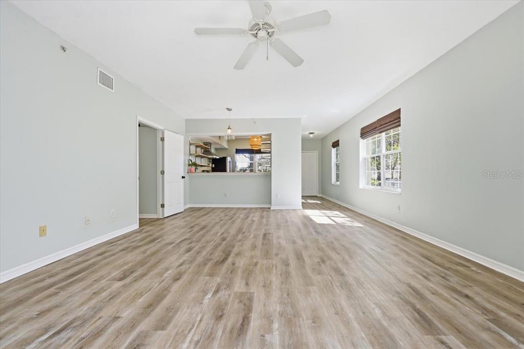 An open-concept living area features light wood-look flooring, pale walls, and a kitchen pass-through window — 70 SAN JUAN DRIVE UNIT D101, PALM COAST, FL