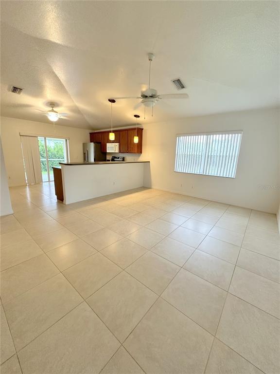 An open-concept living area features light tile flooring, a kitchen island, and vaulted ceilings — 199 ROTONDA BOULEVARD W UNIT C, ROTONDA WEST, FL