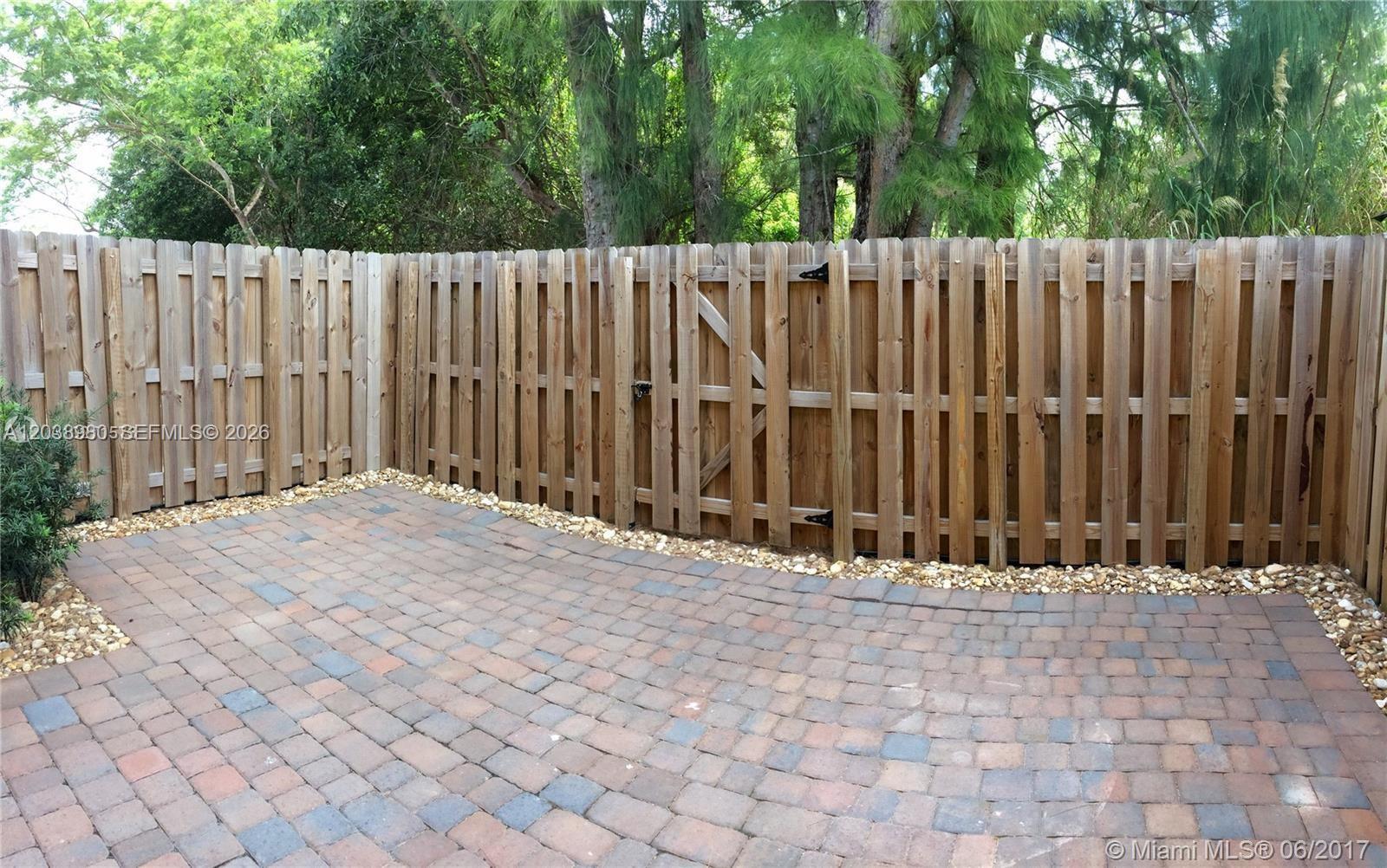 A paved patio area is enclosed by a wooden privacy fence with a gate — 11725 SW 150th Pl # 11725, Miami FL 33196, MIAMI, FL