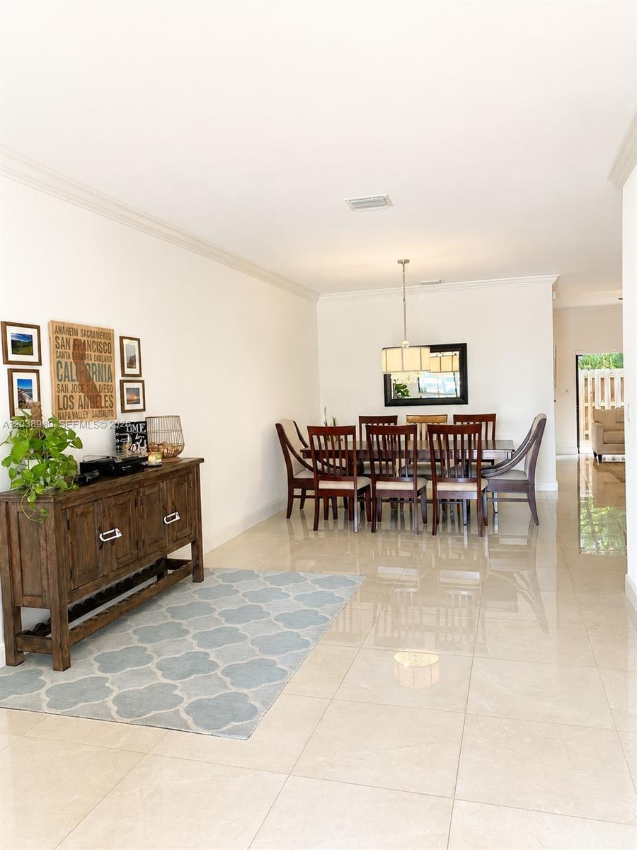 A dining room features a wooden table with eight chairs, a sideboard, and tile flooring — 11725 SW 150th Pl # 11725, Miami FL 33196, MIAMI, FL