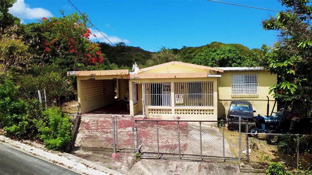 A single-story yellow house with a carport, security bars, and a tractor parked outside — Destino no 3 DESTINO, VIEQUES, PR