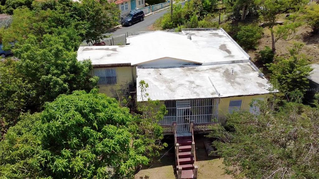 An elevated aerial view shows a single-story house with a white roof and metal security bars — Destino no 3 DESTINO, VIEQUES, PR