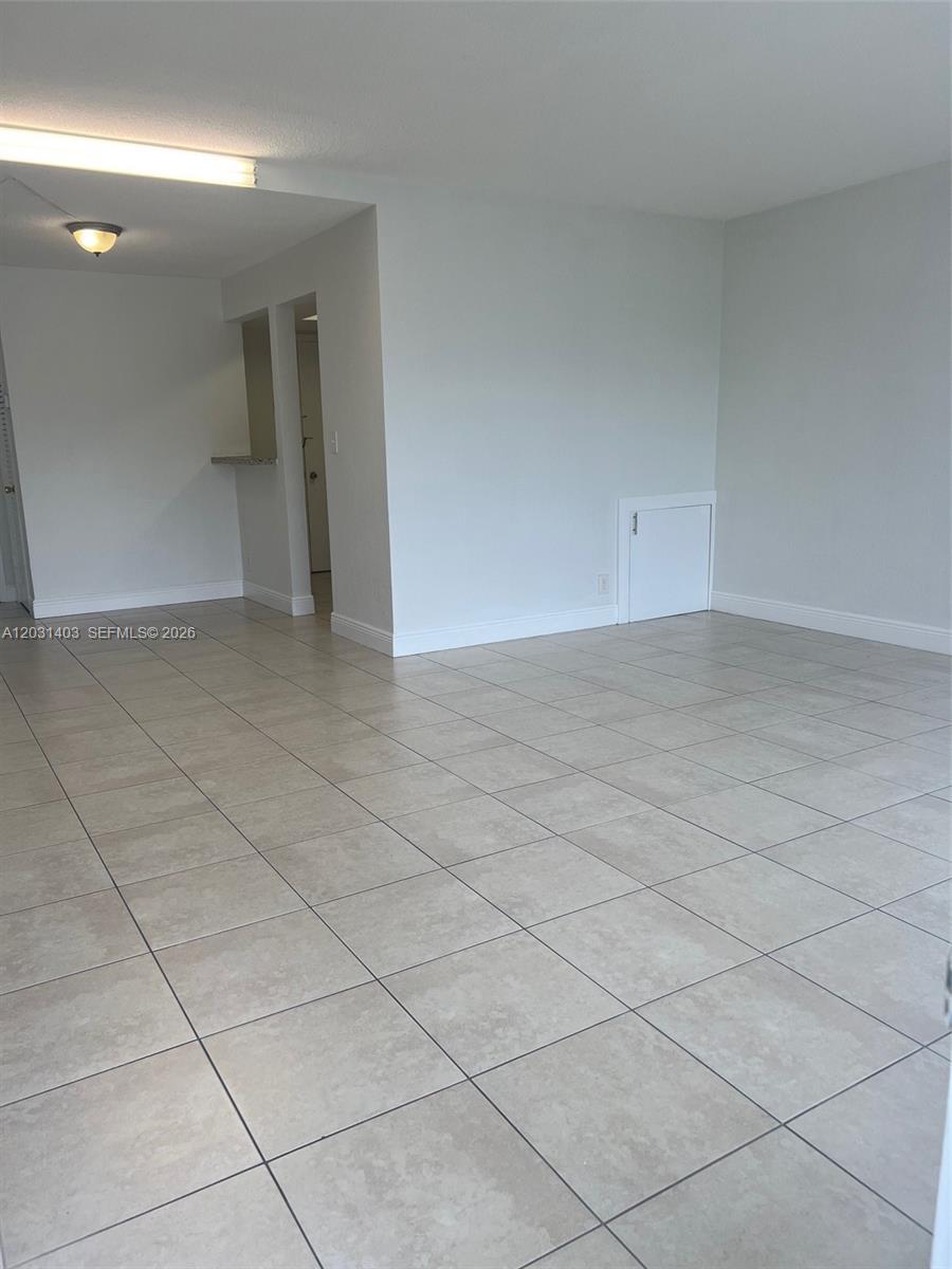 An empty room features light-colored tile flooring, white walls, and a small built-in wall cabinet — 16801 NE 14th Ave # 310, Miami FL 33162, MIAMI, FL