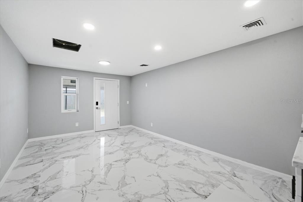 An empty room features gray walls, recessed lighting, and white marble-patterned tile flooring — 6224 KELLER DRIVE UNIT 2, PORT RICHEY, FL