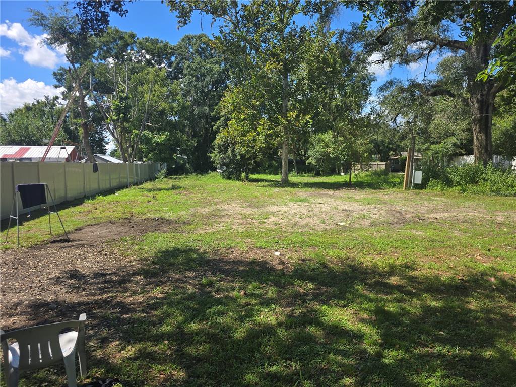 A large, grassy, partially cleared residential lot features scattered trees and a white privacy fence — 1403 GORDON ROAD, PLANT CITY, FL