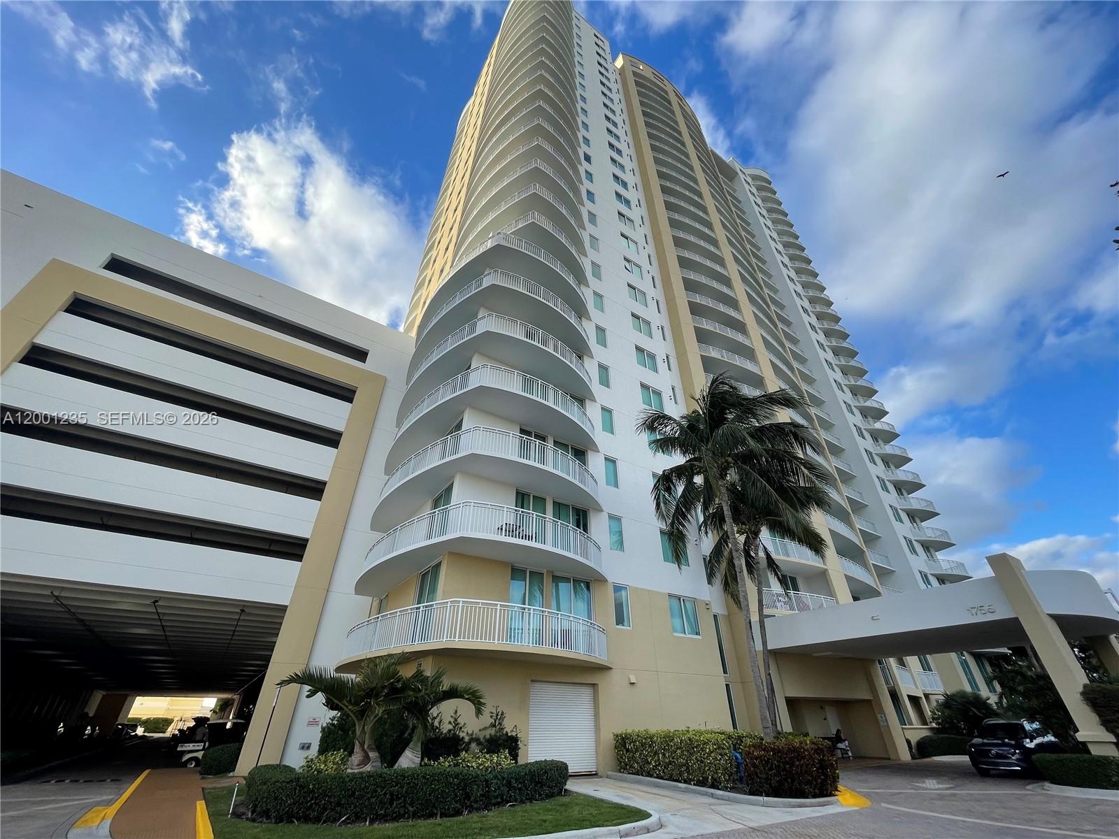 A tall residential high-rise building features curved balconies and an attached parking garage structure — 1755 E Hallandale Beach Blvd # 2002E, Hallandale Beach FL 33009, HALLANDALE BEACH, FL