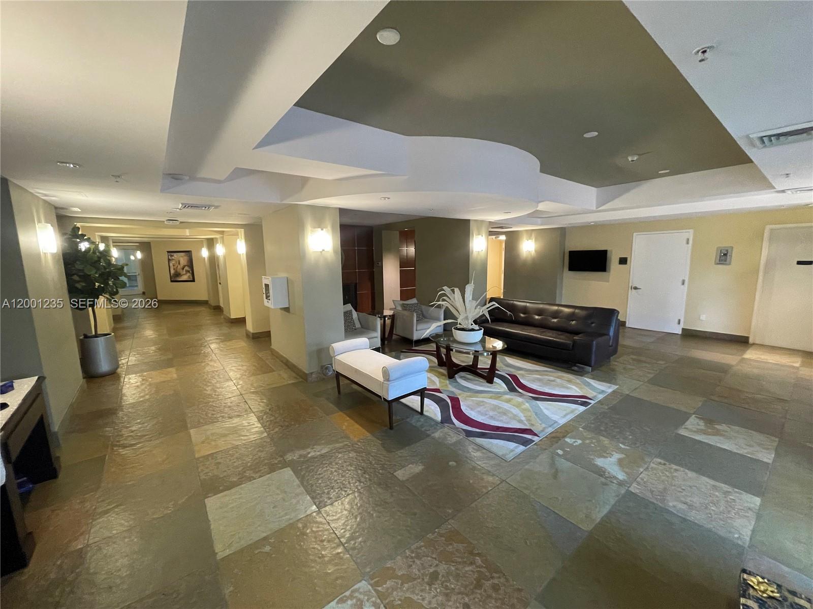 A spacious lobby features stone tile flooring, a seating area with a sofa, and recessed lighting — 1755 E Hallandale Beach Blvd # 2002E, Hallandale Beach FL 33009, HALLANDALE BEACH, FL