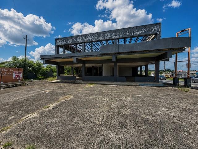 A weathered, multi-story commercial building with an open-air structure stands above a large concrete lot — Calle 28 URB. MIRAFLORES, BAYAMON, PR