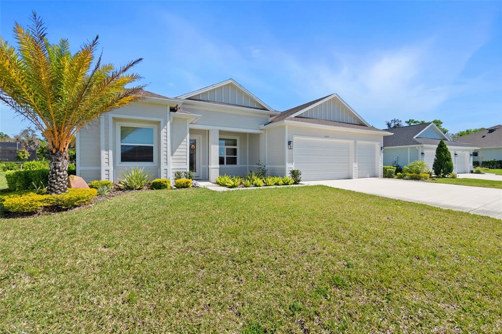 A single-story house with a light-colored exterior, a two-car garage, and a palm tree — 1329 TULLAMORE BOULEVARD, ORMOND BEACH, FL