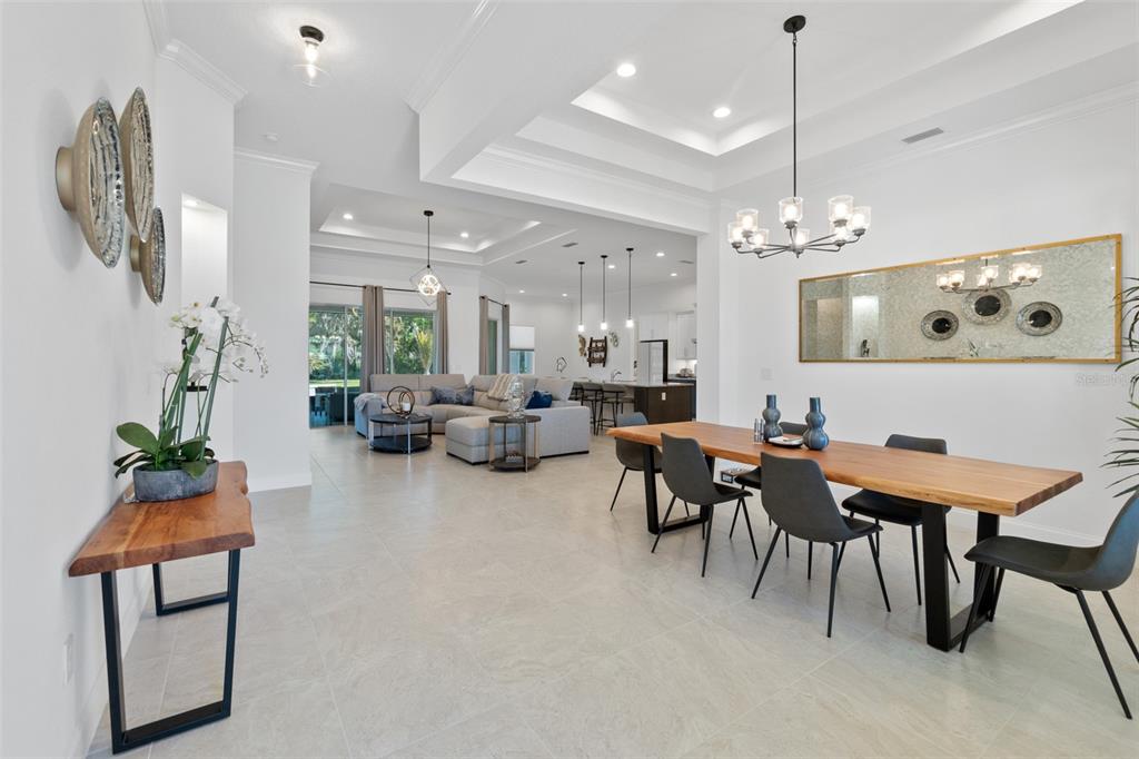 An open-concept living and dining area features tile floors, tray ceilings, and modern light fixtures — 1329 TULLAMORE BOULEVARD, ORMOND BEACH, FL