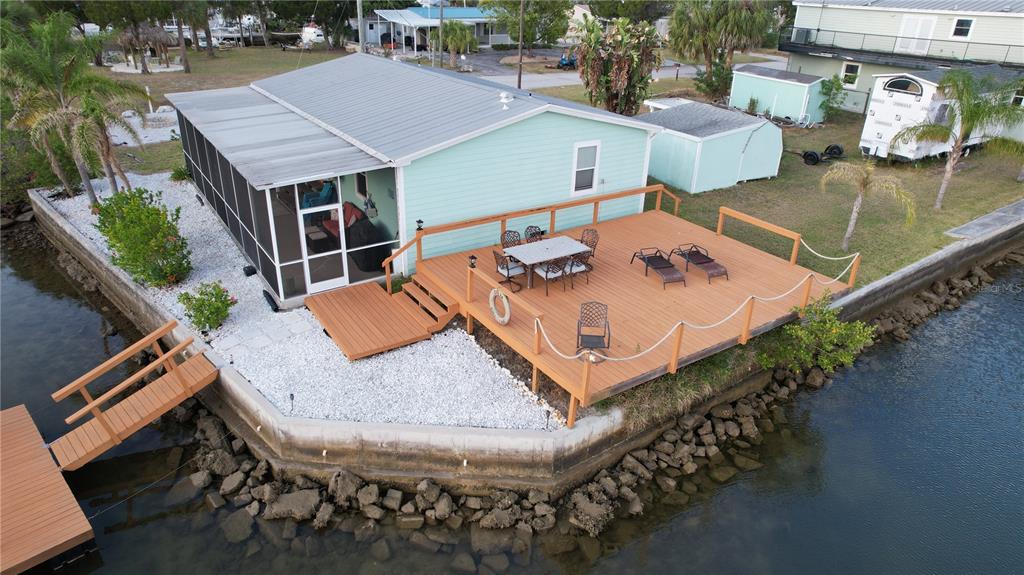 An aerial view of a light blue house with a large wooden deck and dock — 6724 GULL LANE, HUDSON, FL
