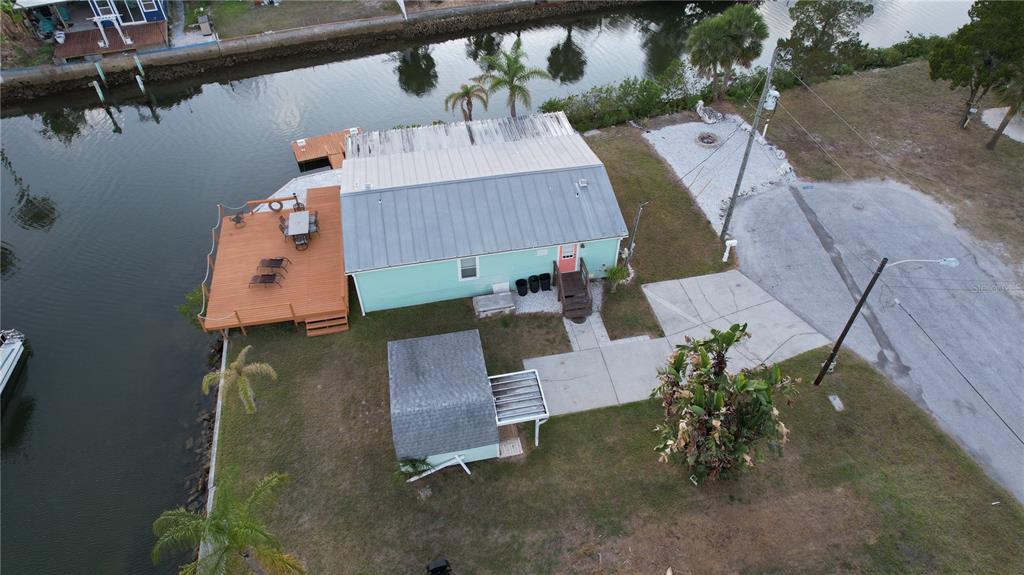 An aerial view shows a light green house with a metal roof, deck, and shed — 6724 GULL LANE, HUDSON, FL