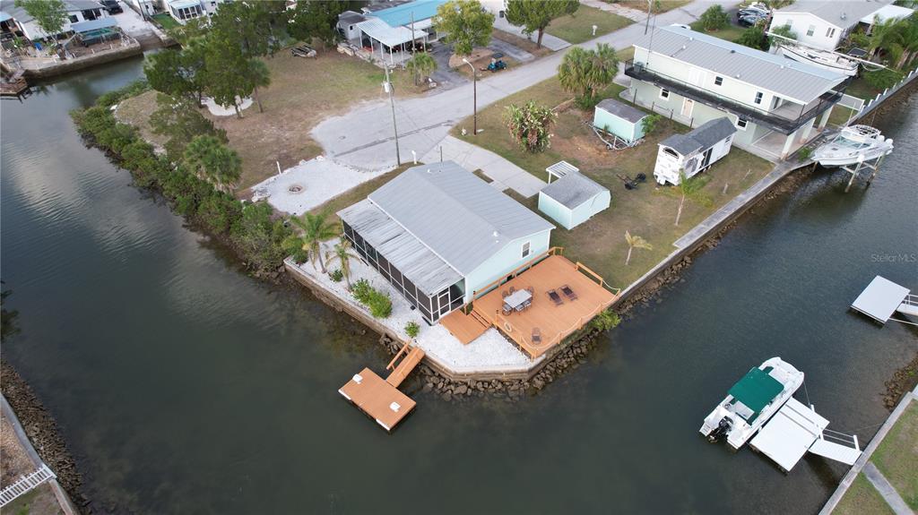 An aerial view shows a waterfront house with a deck, dock, and boat — 6724 GULL LANE, HUDSON, FL