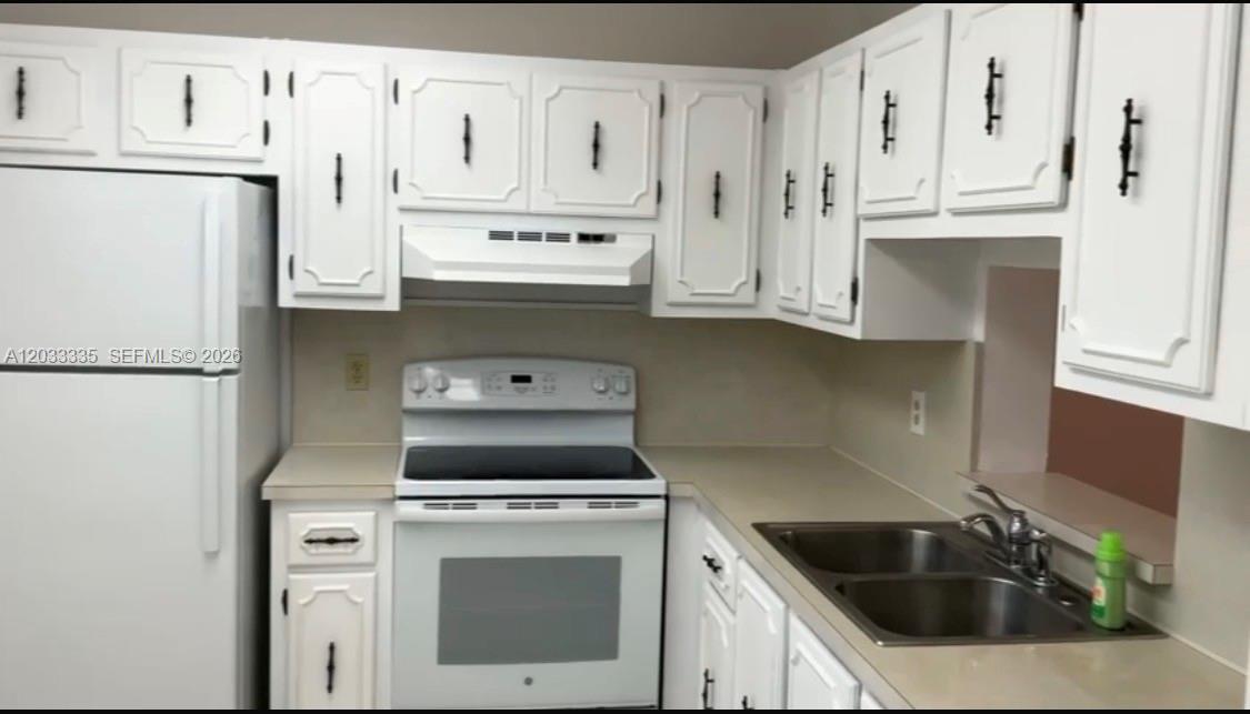 A kitchen features white cabinets, white appliances, and a double-basin stainless steel sink — 201 SE 11th Ter # 302, Dania Beach FL 33004, DANIA BEACH, FL