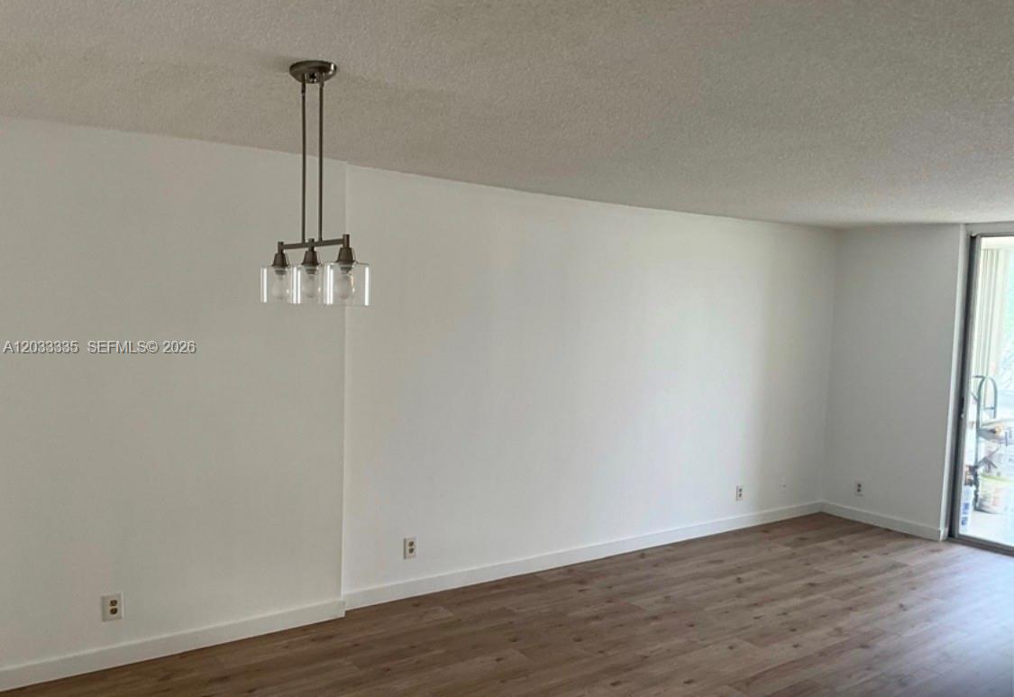 A room with white walls, light wood-look flooring, and a hanging pendant light fixture — 201 SE 11th Ter # 302, Dania Beach FL 33004, DANIA BEACH, FL