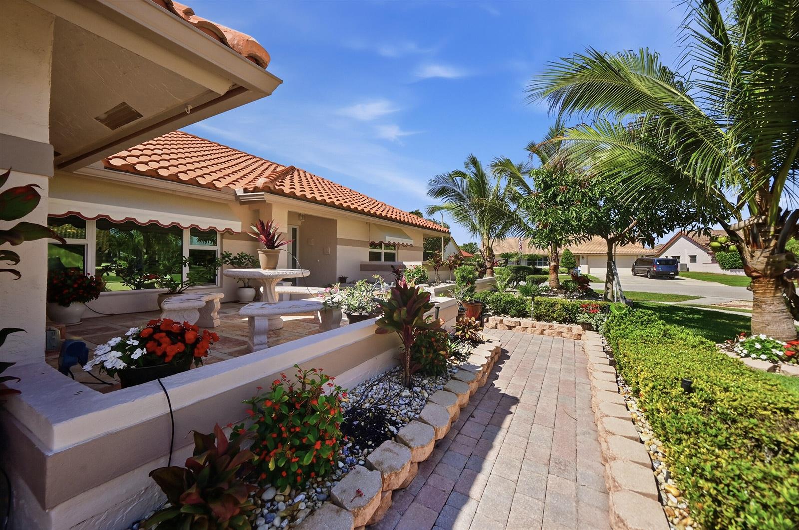 A paved walkway leads past a landscaped garden to a patio with a stone table — 5884 Laurel Green Circle, Boynton Beach FL 33437, BOYNTON BEACH, FL