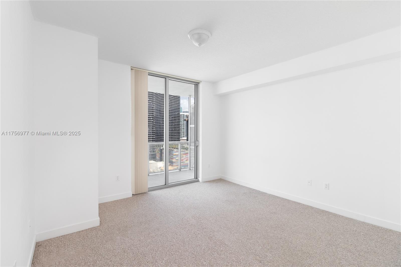 An empty room with white walls, beige carpeting, and a sliding glass door to a balcony — 1111 SW 1st Ave, Miami FL 33130, MIAMI, FL